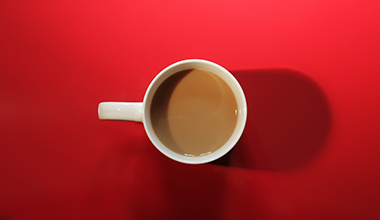 Top view of a coffee cup on a red surface.