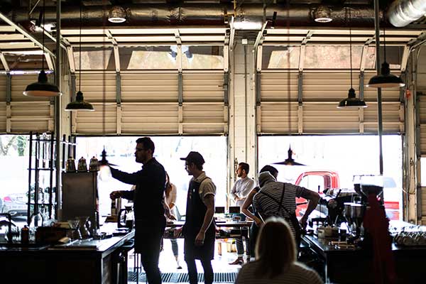 People working in a garage with open doors.